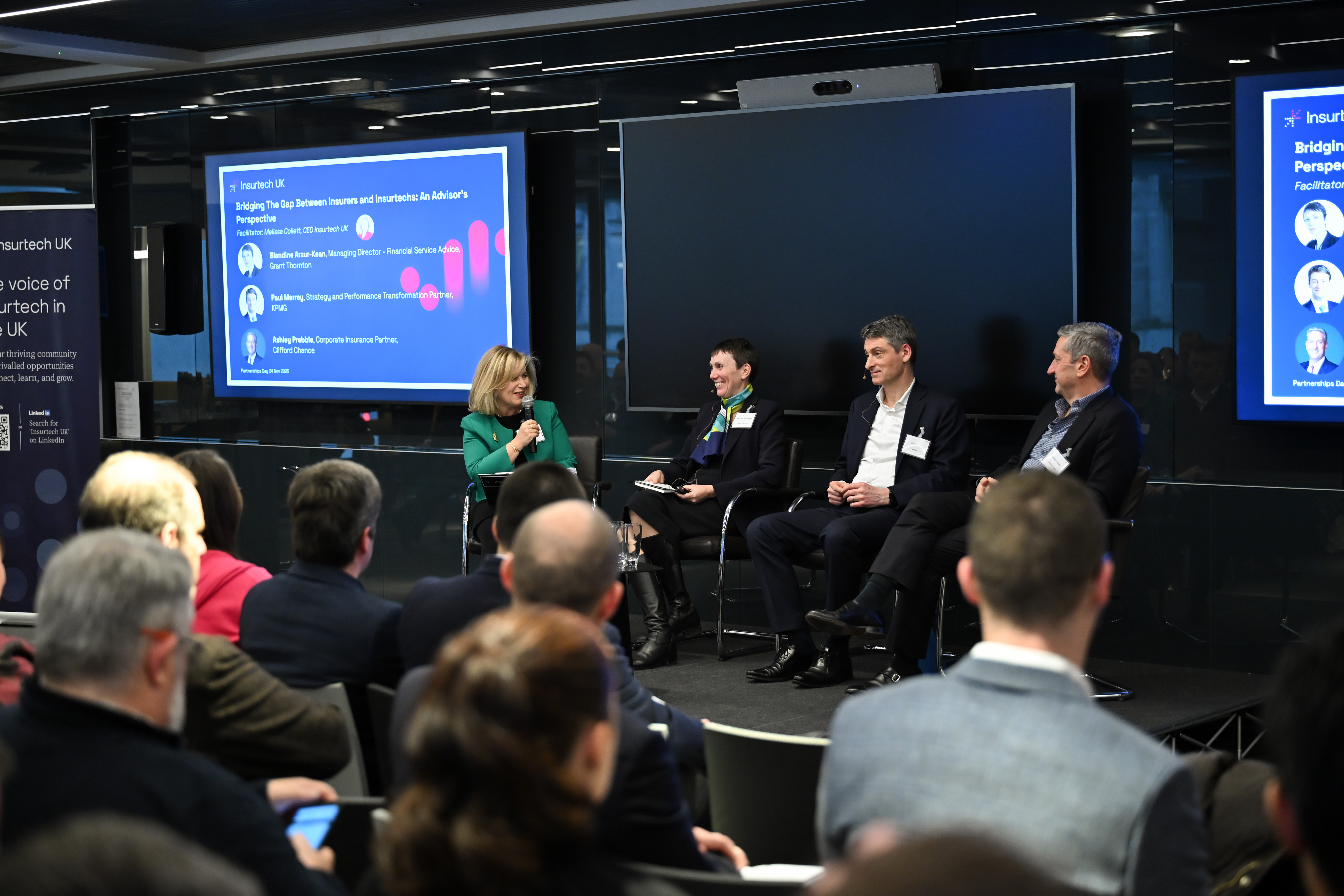 Two women and two men sitting on chairs, one woman with microphone